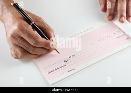 Person&#39;s hand signing a cheque book Stock Photo