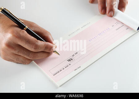 Person&#39;s hand signing a cheque book Stock Photo