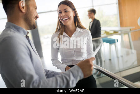 Business people discussing over documents in office lobby. Stock Photo