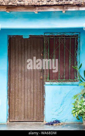 Trinidaad, Cuba Nov 26, 2017 - Brown door and grated window on blue wall Stock Photo