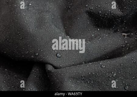 dark gray waterproof hydrophobic cloth closeup with rain drops selective focus background Stock Photo