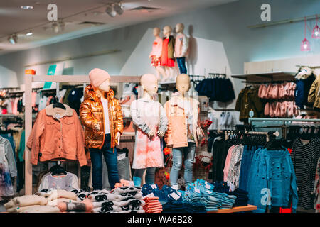 Mannequins Dressed In Children Female Casual Clothes And Colorful Bright Children Clothes On Shelves And Hanger In Store Of Shopping Center. Stock Photo