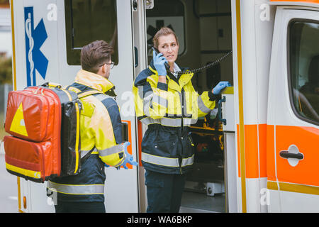 Medics in front of ambulance talking to headquarters using radio Stock Photo