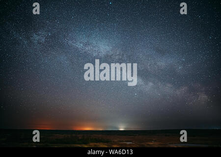 Night Starry Sky With Glowing Stars Above Forest Landscape. Dark Night Starry Sky Above Ground. Stock Photo