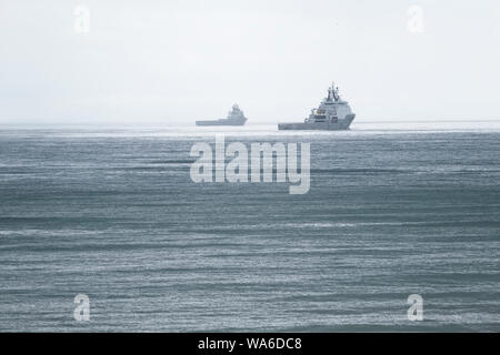 Ship on horizon under dark grey sky during a sea storm Stock Photo