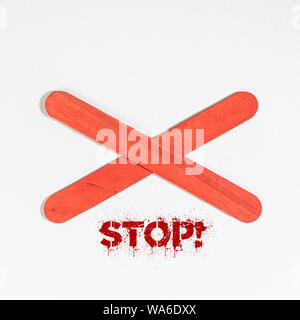 the word Stop under an X of red wood on a white surface Stock Photo