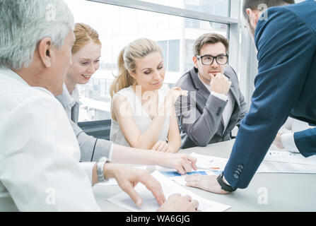 Group of business people discussing diagrams in office together Stock Photo