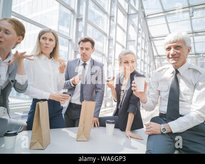 Business people having coffee break eating donuts together in office Stock Photo