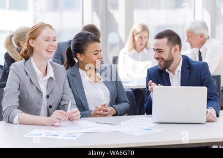Business team sitting by the table with laptop and documents in office Stock Photo