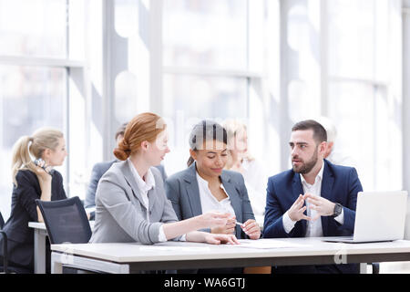 Business team sitting by the table with laptop and documents in office Stock Photo