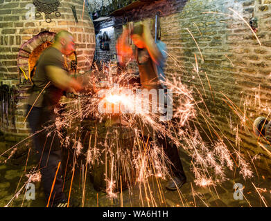 Bukhara, Uzbekistan - May 22, 2017 - Two blacksmiths use hammers to beat hot metal as sparks fly Stock Photo