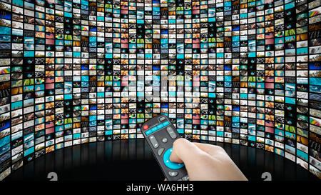 Image of big screen with many channels, hands of man with remote control . Stock Photo