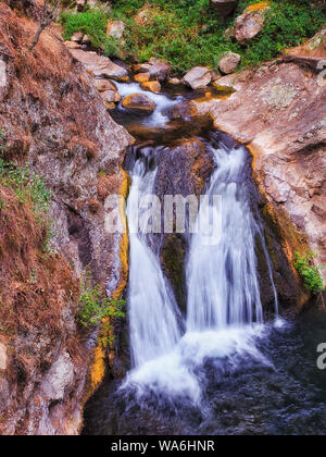 Small waterfall on Jenolan river between sandstone rocks in BLue Mountains falling down to small pond in two streams. Stock Photo