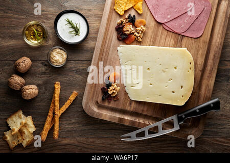 Aged cheese on wooden table with wooden cutting board, knife and props. Overhead view. Stock Photo