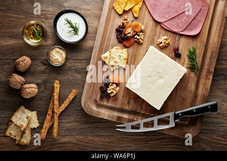 Turkish bryndza sheep milk cheese on wooden table with wooden cutting board and knife. Overhead view. Stock Photo