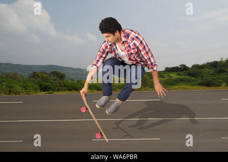 Young man performing jump on skateboard Stock Photo