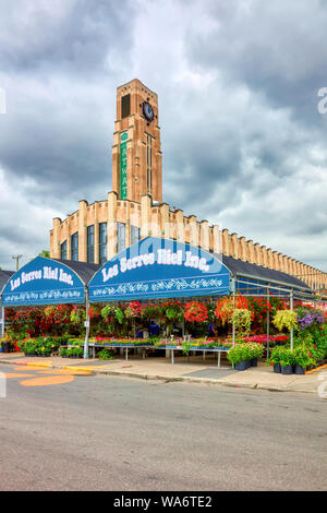 Exterior view of Atwater Market building and its clock tower with flower shops around in Montreal, Quebec, Canada. Stock Photo