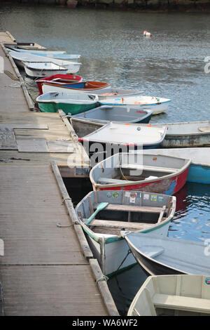 colorful tender boats tied to a weathered dock in calm waters Stock Photo