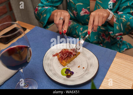 woman cuts dishes according to the rules of etiquette in a green dress close-up Stock Photo