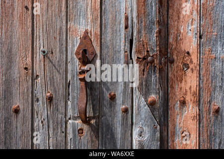 Rusty latch on weathered wooden door - France. Stock Photo