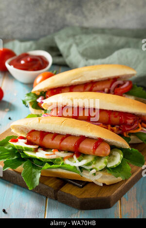 Traditional american fast food. Barbecue grilled Hot dog with fresh vegetables on wooden table with copy space. Stock Photo