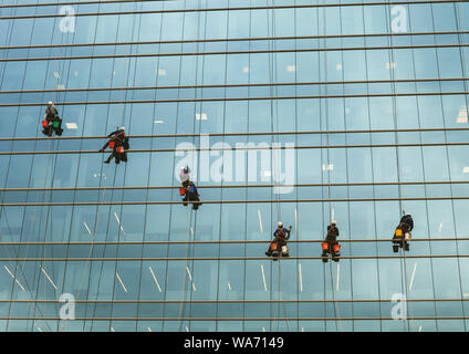 group of workers cleaning windows service on high rise building. window washers industrial climbers Stock Photo