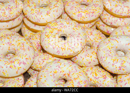 donuts with white icing and colored crumbs on the counter close-up Stock Photo