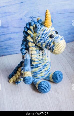 Crocheted unicorn blue of melange threads are yellow elements. A nice toy handmade. . Stock Photo