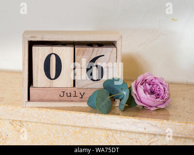 Wooden date cubes on July 6 and a rose blossom Stock Photo