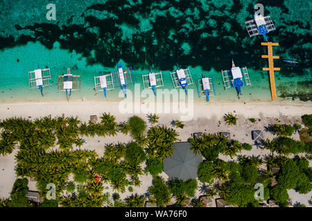 Aerial drone view of traditional Banca boats moored next to a tiny, tropical island surrounded by coral reef (Kalanggaman Island) Stock Photo