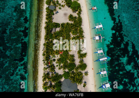 Aerial drone view of traditional Banca boats moored next to a tiny, tropical island surrounded by coral reef (Kalanggaman Island) Stock Photo
