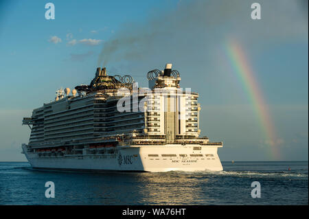 MIAMI - AUGUST 11, 2019: Brown exhaust smoke from the MSC Seaside cruise ship covers a rainbow as it departs PortMiami. Stock Photo