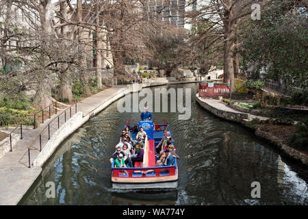 A barge loaded with tourists at the River Walk, also known as the Passeo del Rio, a network of walkways along the banks of the San Antonio River, one story beneath the streets of Downtown San Antonio, Texas Stock Photo