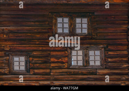 background - wall of an old wooden log building with several windows Stock Photo