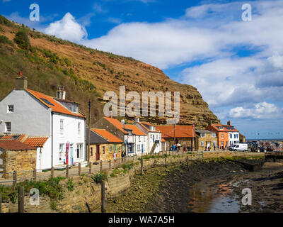 Row of holiday cottages by Staithes Harbour on the north bank of Roxby Beck adjacent to the RNLI Lifeboat Station Stock Photo