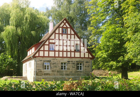 romantic old house built with natural stones and framework, surrounded by large trees Stock Photo