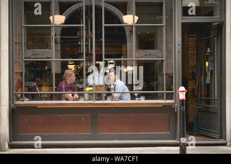 London, UK - August, 2019. View of people having coffee in a coffee shop through the shop window in central London. Stock Photo