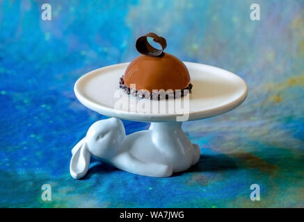 A delicious chocolate pastry rests on a whimsical bunny cake stand Stock Photo