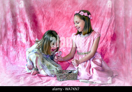 a little girl looks in a mirror held by her big sister, and laughs at how pretty she looks Stock Photo
