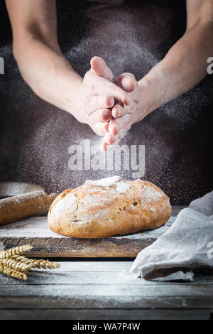 Baker cooking bread. Man slaps flour over the dough. Man's hands Making bread Stock Photo