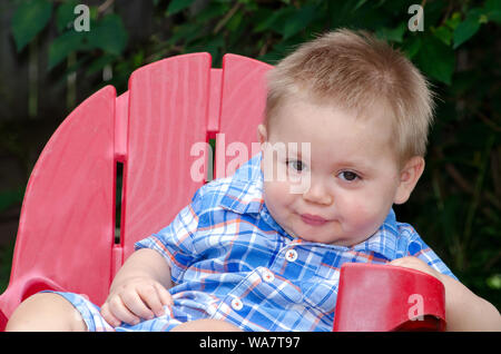 baby boy in a red chair, making a funny face Stock Photo
