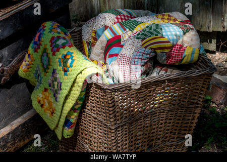 old wicker basket filled with hand made quilts and blankets Stock Photo