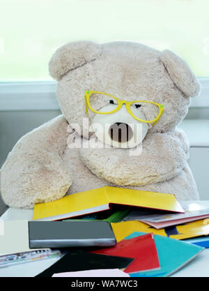 Bear with big glasses reads a stack of colorful books. reading is power! Stock Photo