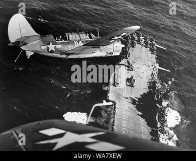 Curtiss SB2C Helldiver, a carrier-based dive bomber aircraft during World War 2. Curtiss SB2C-3 Helldiver aircraft banks over the USS Hornet (CV-12), aircraft carrier before landing, following strikes on Japanese shipping in the China Sea, circa 1945 Stock Photo