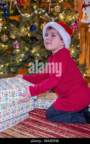 little boy is caught trying to open Christmas gifts Stock Photo