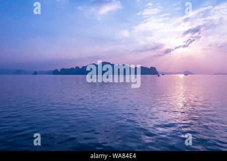 Fairy tale landscape of the Halong Bay karst island formations at sunset with a sunbeam, Haiphong province, North Vietnam. Stock Photo