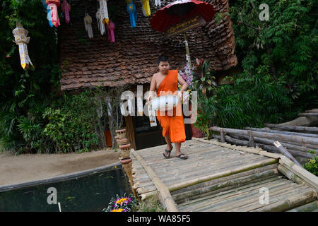 A young monk from the Buddhist temple Wat Phan Tao carrying a bowl with rice to prepare food during the annual Loy Krathong festival. Chang Wat, Chiang Mai, Chiang Mai Province, Thailand, South East Asia Stock Photo