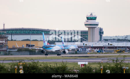 A Tui Airways Boeing 757-200 plane turns off the runway in front of the air traffic control tower and the Gatwick Pier 6 Bridge Stock Photo