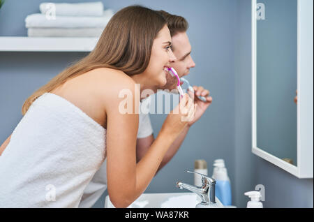Portrait of happy young couple brushing teeth in the bathroom Stock Photo