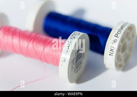 Umea, Sweden - August 15, 2019: two rolls of sewing thread pink and blue in close-up at Umedalen with white background in studio light Stock Photo